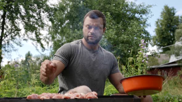 a Young Man Puts Skewers with Raw Meat on the Grill