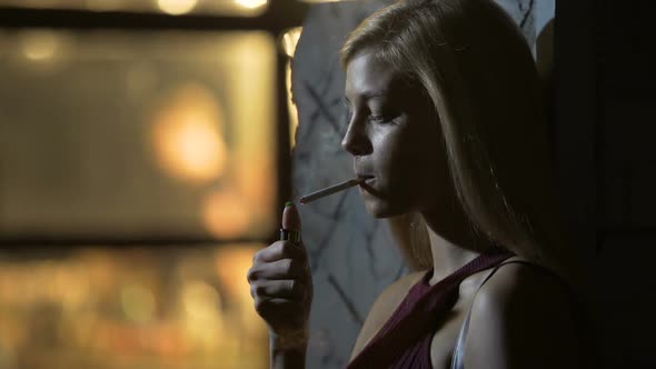 Beautiful Sexy Female Lighting a Cigarette and Inhaling Smoke, Night Life