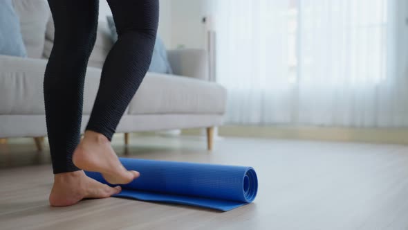 Close up of sportswoman feet roll out exercise mat to start work out by doing yoga stretching body.