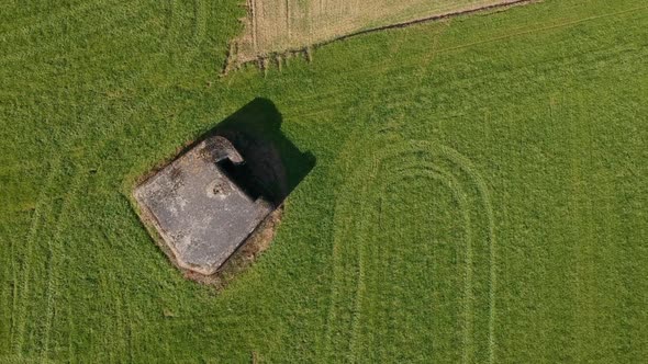 Topdown aerial over WW2 WWII bunker green field sunny dark shadows day