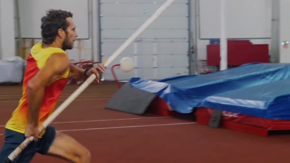 Pole Vaulting Indoors - a Man in Yellow Shirt Running Up and Jump Over the Bar