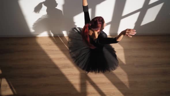 Ballerina in Black Tutu Gracefully Dances Against White Wall in Bright Sunlight