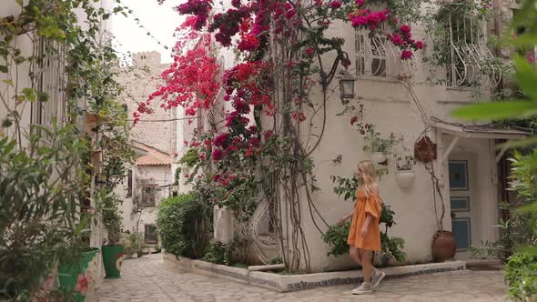 Woman Walking Near Stunning Flowers on the Wall On Popular Greece Resort During Vacation.