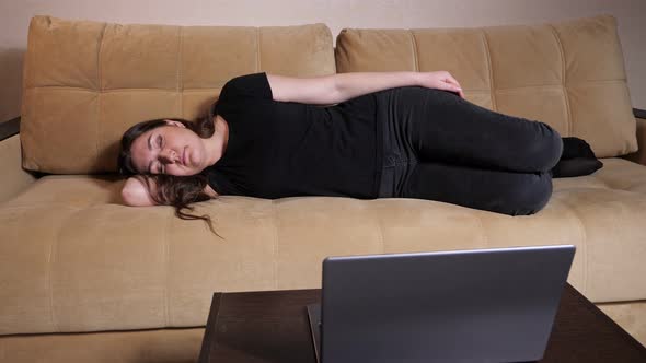 Young Woman in Black Tshirt and Denim Jeans Sleeps on Sofa