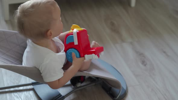 Cute Small Child Sitting in Baby Bouncer Playing with Plastic Toy Car One Year Old Baby Boy Playing