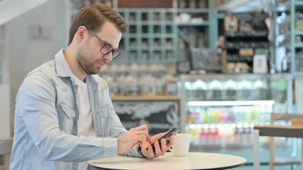 Man Using Smartphone in Cafe