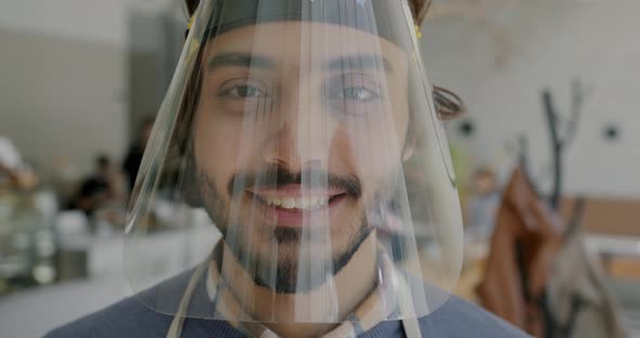 Slow Motion Portrait of Arab Guy Waiter Wearing Face Shield and Smiling Indoors in Cafe