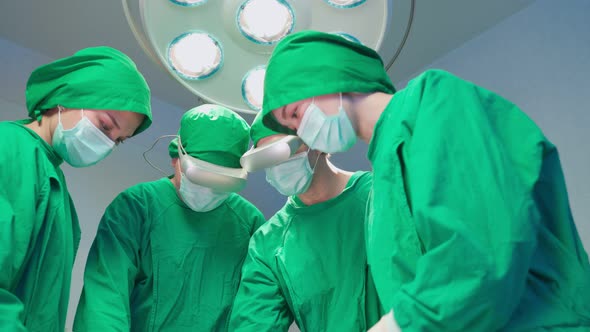 Professional doctor medical team performing surgical operation for patient in modern operating room.