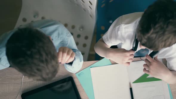 Highangle Shot Children Little Boys Discuss School Homework Sitting at a Table