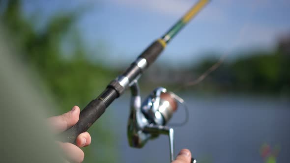 Closeup Fishing Rod Spinning Reel with Male Caucasian Hand Rolling Equipment Catching Freshwater