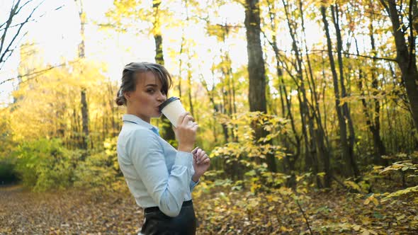 Woman spending time in park. Young woman spending time with cup of coffee in autumn park