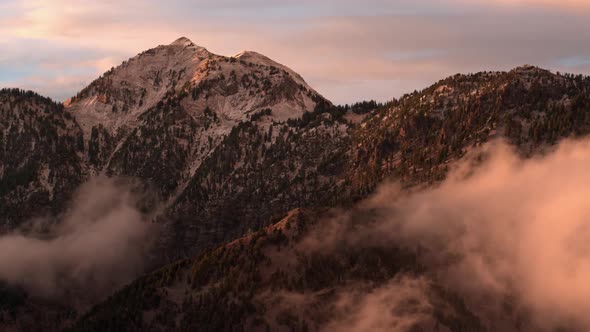 Aerial view of low clouds below mountain tops at sunset