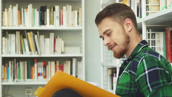 A Laughing Guy Is Sitting in the Library and Reading