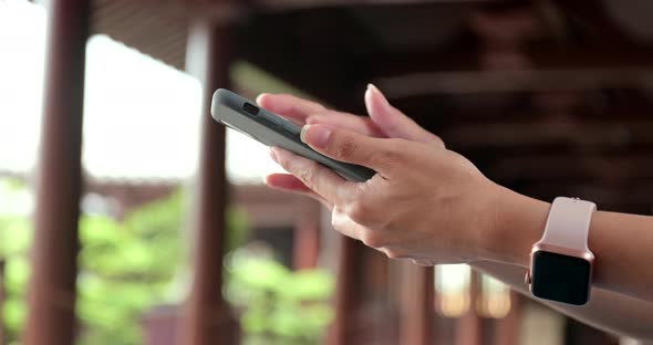 Close up of using mobile phone in Chinese garden