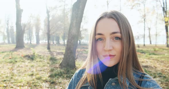 Portrait of Young Attractive Female Looking at the Sliding Camera on Autumn Park. Cheerfully Pretty