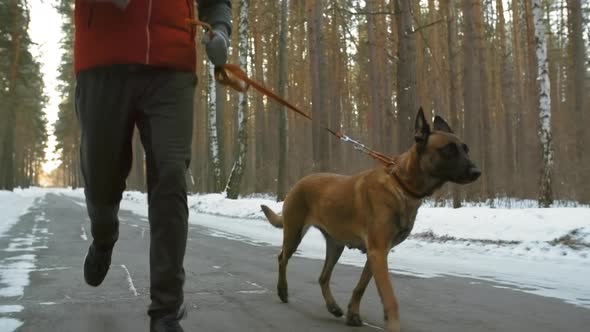 Man Running with Dog in Winter Woods