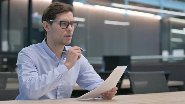 Young Man Celebrating Success While Reading Documents