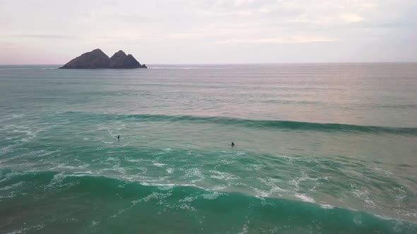 A surfer attempts to catch a wave. Drone-shot.