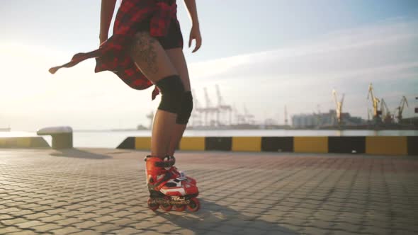 Young Stylish Funky Girl with Green Hair Riding Roller Skates and Dancing Near Sea Port During