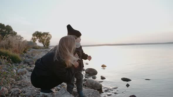 Woman Talking to Her Child on the Stone Shore a of Lake on an Autumn Evening