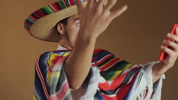 Young Mexican In Multicolored Poncho And Hat