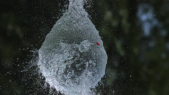 700012 Shot breaking water filled Red balloon, slow motion