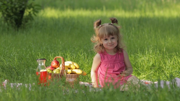 Weekend at Picnic. Lovely Caucasian Child Girl on Green Grass Meadow Eating Merry, Cherry