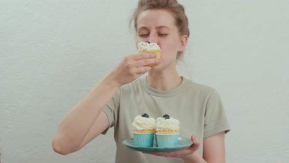 Young Woman Eating Birthday Cupcakes and Looking at the Camera and Smiling