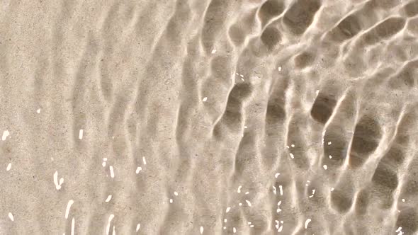 Slow Motion Closeup Water Surface Texture Splash and Ripples on Sand Background