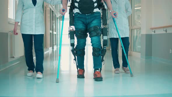 Hospital Hall with a Man Walking in the Exoskeleton with Assistance