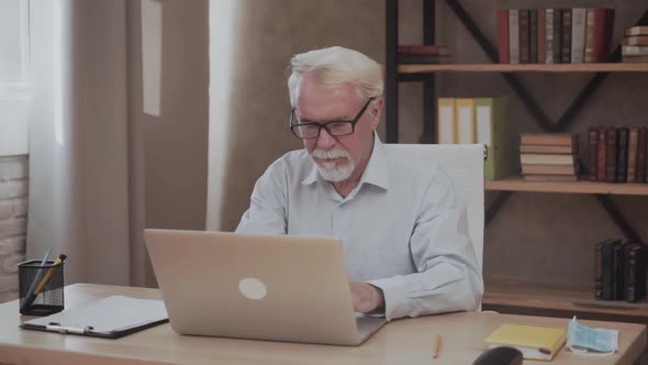 Bearded Senior Man Working with Laptop in Office