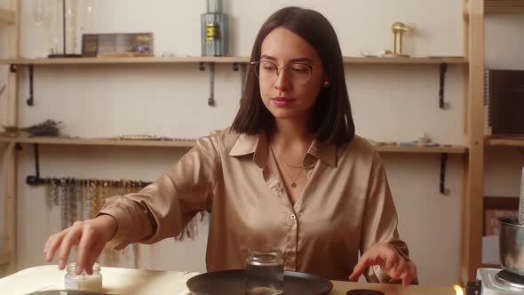 Portrait of Attractive Young Woman Artisan Preparing Glass Vessel to Pour Mixture of Liquid Wax to