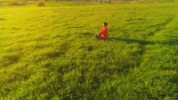 Low Altitude Radial Flight Over Sport Yoga Man at Perfect Green Grass. Sunset in Mountain