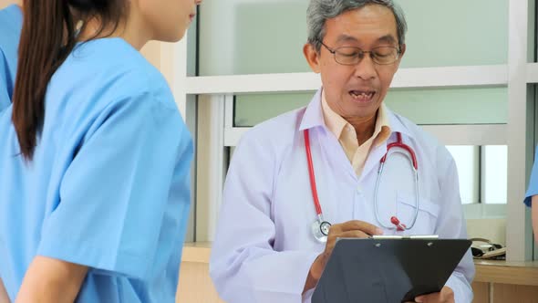 Team of asian doctor nurse consult together on patients file at hospital.