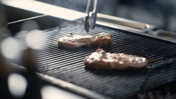 Close Up Turning Meat Steak on Grill Surrounded By Steam