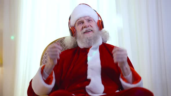 Front View Cheerful Happy Santa Clause Gesturing Singing Listening to Music in Headphones Sitting