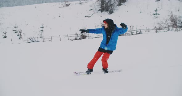 Male Snowboarder Rides on a Board in the Snow From the Ski Slope