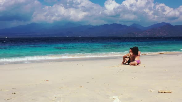 Boy and girl sunbathe on relaxing island beach trip by clear sea with white sandy background of Gili