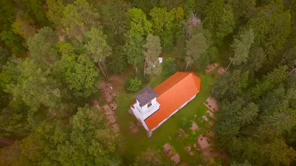 Aerial view of a traditional Chapel surrounded by a cemetery and a forest in Estonia.
