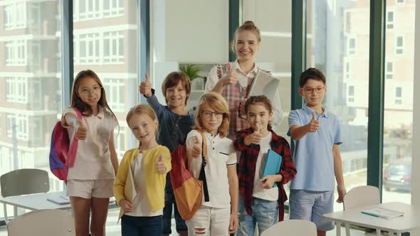 Portrait of the Children Stand with the Teacher in the Middle of the Class and Show a Finger Up