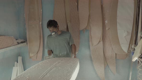 Indonesian Worker Using Sandpaper for Making Surfboard