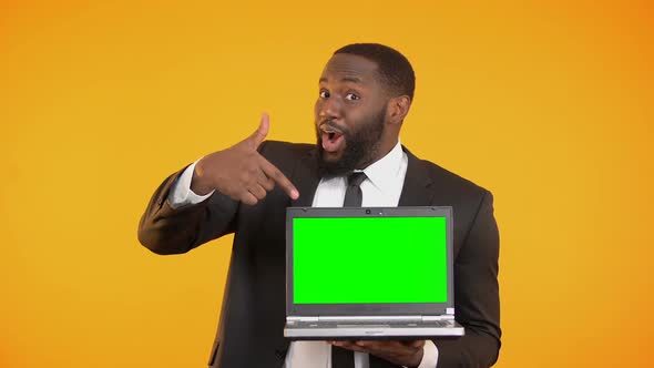 Smiling Afro-American Salesman Showing Prekeyed Laptop, Place for Advertisement