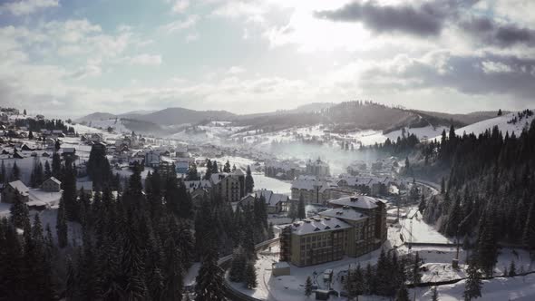 Aerial Footage of Small Mountain Village in Winter Time During Sunny Day with Epic Clouds