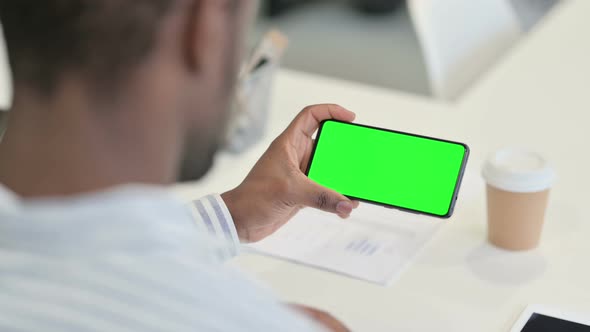 Rear View of African Man Using Smartphone with Green Chroma Screen