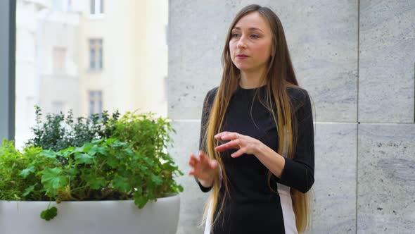 Young Woman with Long Hair Actively Gesturing While Giving a Stand Up Talk