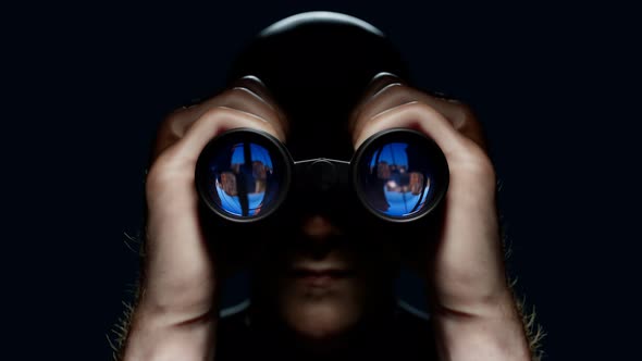 A man looking through binoculars. A guy with field glasses watching a target.