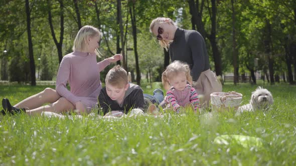 Portrait Young Family Outdoor Recreation. Two Beautiful Young Mothers and Their Children at a Picnic