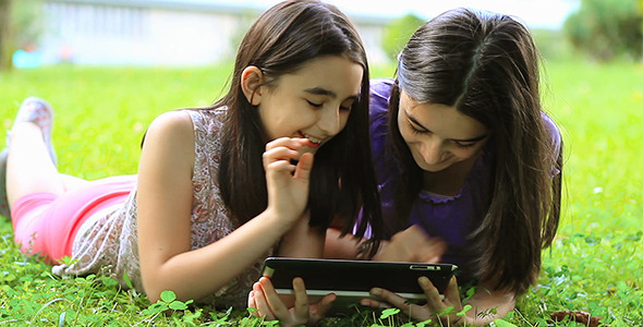 Girls Playing on Digital Tablet Outdoors 