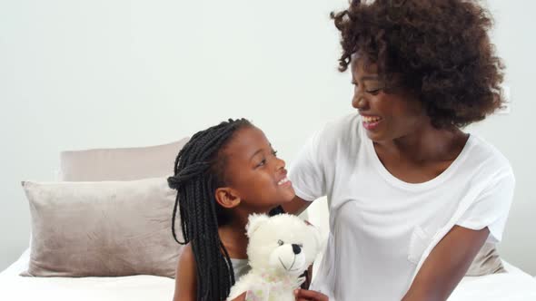 Mother hugging daughter in bedroom