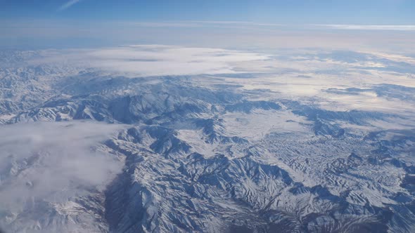 Distant Mountain Range Against Blue Sky From Airplane Window